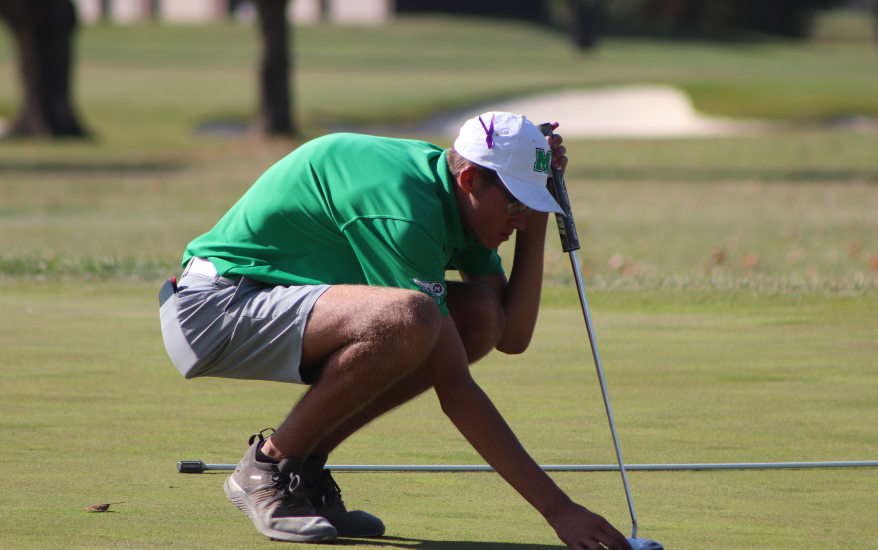 boy picking up golf ball out of hole